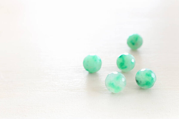 green gemstones beads on white wooden background