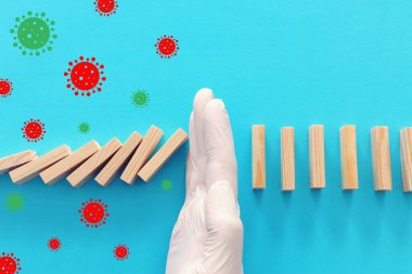 Domino etkisini durduran eldiven giymiş bir erkek. covid 19 veya coronavirus engelleme kavramı