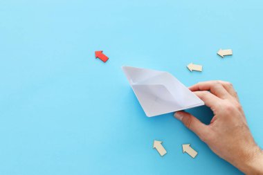 Erkek el, mavi arka planda kağıt tekneyi yönetiyor. dogru dogru dogruyu bulmak ve ilerlemek konsepti.