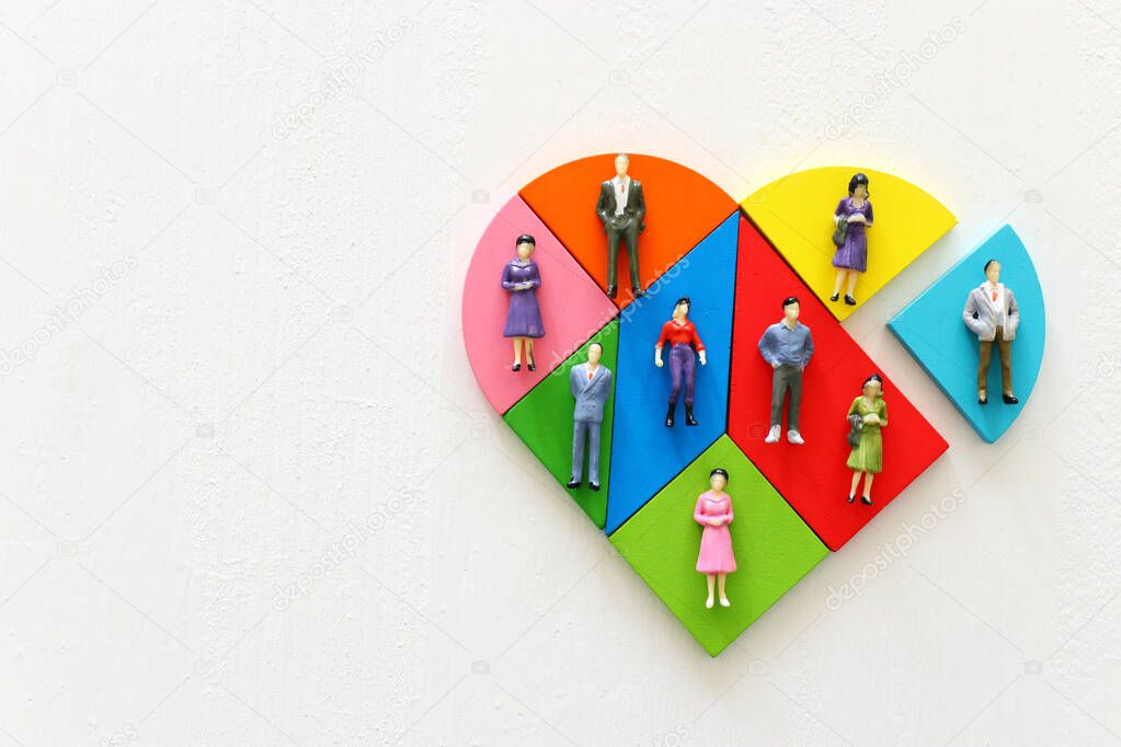 Unity and diversity partnership concept. heart shaped puzzle and group of diverse miniature people connected