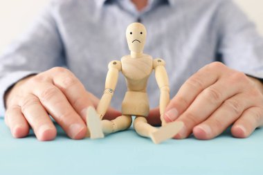 Erkek eli, üzgün yüzlü tahta kuklayı tutuyor. Anksiyete, stres ya da hüzünlü duygular kavramı