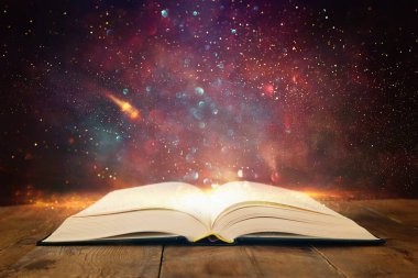 Tahta masanın üzerinde parıltılı kaplamalı açık antik kitap görüntüsü