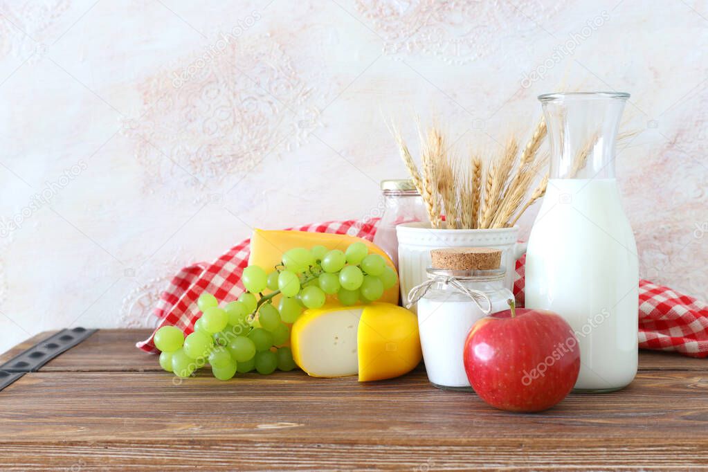 photo of dairy products over old wooden table and white background. Symbols of jewish holiday - Shavuot