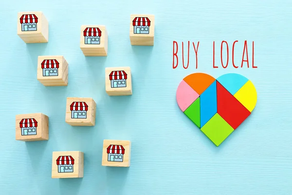 Concept of supporting local business during coronavirus outbreak. Heart shape and wooden cubes with stores icon