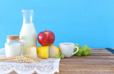 Eski ahşap masa ve mavi arka planda süt ürünlerinin fotoğrafı. Yahudi bayramının sembolleri - Shavuot