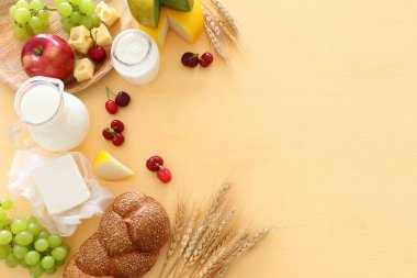 Süt ürünlerinin en üstteki fotoğrafı pastel sarı arka planda. Yahudi bayramının sembolleri - Shavuot