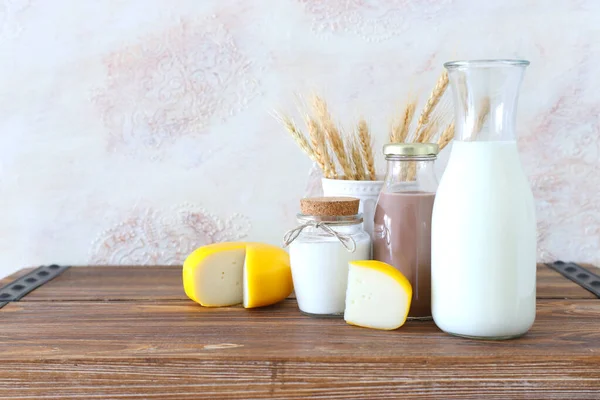 photo of dairy products over old wooden table and white background. Symbols of jewish holiday - Shavuot