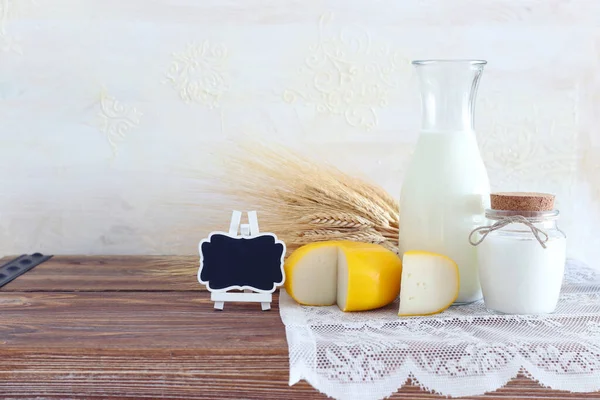 photo of dairy products over old wooden table and white background. Symbols of jewish holiday - Shavuot