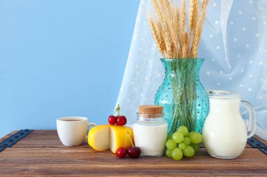 Eski ahşap masa ve pastel arka planda süt ürünlerinin fotoğrafı. Yahudi bayramının sembolleri - Shavuot