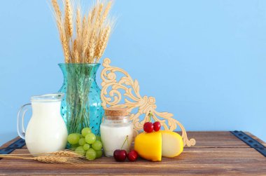 Eski ahşap masa ve pastel arka planda süt ürünlerinin fotoğrafı. Yahudi bayramının sembolleri - Shavuot