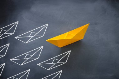 Karatahta arka planında kağıt tekne olan liderlik kavramı. Bir lider gemi diğer gemileri yönetiyor..
