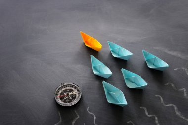 Karatahta arka planında kağıt tekne olan liderlik afişi konsepti. Bir lider gemi diğerlerine liderlik eder.