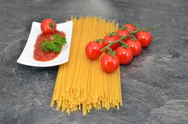 Domatesli çiğ spagetti ve koyu arkaplanda fesleğen.