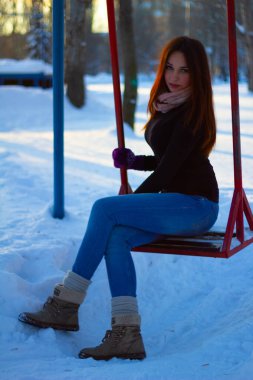 Kış akşamında bir kızın portresi. Kız salıncakta oturuyor