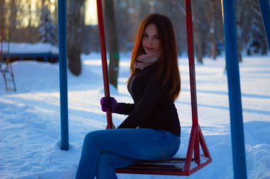 Kış akşamında bir kızın portresi. Kız salıncakta oturuyor