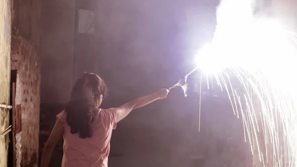 Concéntrate en las chispas. Mujer vista trasera sosteniendo palo de fuegos artificiales y celebrando el festival Diwali con bengalas en la noche en el fondo de la ciudad. Feliz Dipawali. Calcuta, Bengala Occidental, India, Asia Meridional Pac . — Foto de Stock