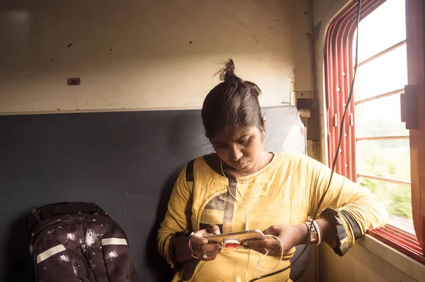 Mujer usando el teléfono móvil mientras viaja solo en tren de pasajeros. Viajero disfrutando de la tecnología moderna en movimiento en la vida cotidiana y los viajes. Retrato de cerca - Señora joven adulta - Etnia india . — Foto de Stock