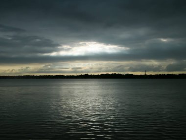 Güzel güneş ışınları karanlık bulutların deliğinde parlıyor ve gün batımında göl suyu ufkunu aydınlatıyor. Teksas 'ın dramatik gökyüzü atmosferi. Doğada güzellik.