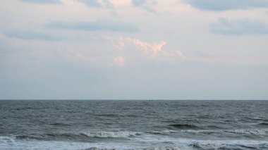 Deniz dalgaları su üzerinde ufuk çiziyor. Okyanus dalgası sürekli ileri, su yukarı, aşağı ve geri hareket eder. Arka planda dramatik bulut gökyüzü. Su yüzeyindeki boşluğu kopyala.