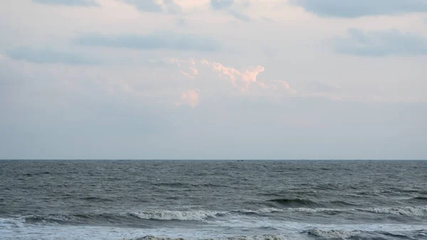 Horyzont fal morskich nad wodą. Fala oceaniczna porusza się nieustannie do przodu, woda porusza się w górę, w dół i z powrotem w ruchu orbitalnym. Dramatyczne niebo chmur w tle. Przestrzeń kopiowania na powierzchni wody. — Zdjęcie stockowe
