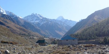 Himalayalar 'ın yüksek dağlarında dağcılara, dağcılara ve dağcılara barınak sağlamak için kurulmuş bir dağ kulübesi. Arka planda iç içe geçmiş bir çıkıntı tepe sırtları V şeklindeki vadi..