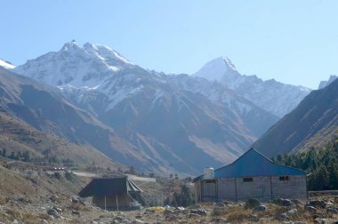 Himalayalar 'ın yüksek dağlarında dağcılara, dağcılara ve dağcılara barınak sağlamak için kurulmuş bir dağ kulübesi. Arka planda iç içe geçmiş bir çıkıntı tepe sırtları V şeklindeki vadi..