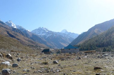 Himalayalar 'ın yüksek dağlarında dağcılara, dağcılara ve dağcılara barınak sağlamak için kurulmuş bir dağ kulübesi. Arka planda iç içe geçmiş bir çıkıntı tepe sırtları V şeklindeki vadi..
