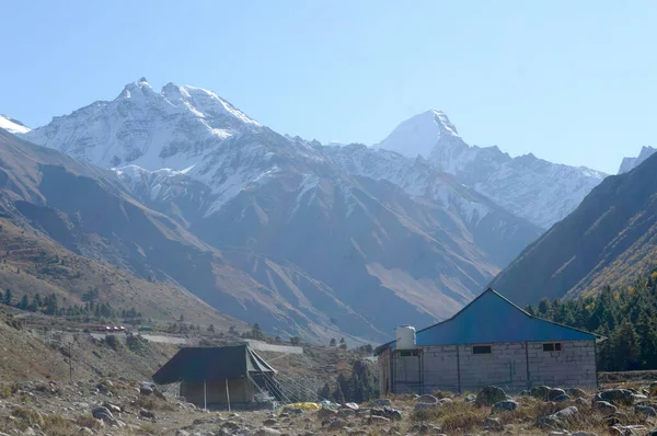 Himalayalar 'ın yüksek dağlarında dağcılara, dağcılara ve dağcılara barınak sağlamak için kurulmuş bir dağ kulübesi. Arka planda iç içe geçmiş bir çıkıntı tepe sırtları V şeklindeki vadi..