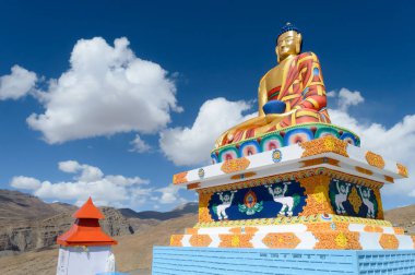 Büyük Himalaya Dağları 'na bakan köyün yukarısındaki tepecikte oturan meditasyon yapan Lord Buddha' nın dev heykeli. Langza, Fosil Köyü Spiti Vadisi, Himachal Pradesh Hindistan