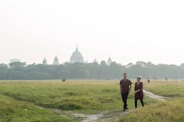 Touristenpaar spaziert im Maidan-Spielgarten des Brigade-Paradeplatzes bei Sonnenuntergang im Sommer. Berühmtes Viktoria-Denkmal vor einer fernen Wiesenkulisse. kolkata west bengal indien Mai 2019 — Stockfoto