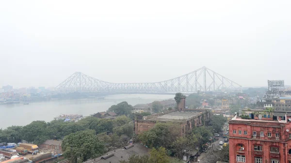 Vista aerea Cityscape Howrah Bridge (Rabindra Setu) della vita cittadina di Calcutta sulla riva del fiume Hooghly vicino alla zona di Burrabazar in una nebbiosa giornata serale invernale. Kolkata West Bengal India Asia Meridionale Pac gennaio 2020 — Foto Stock