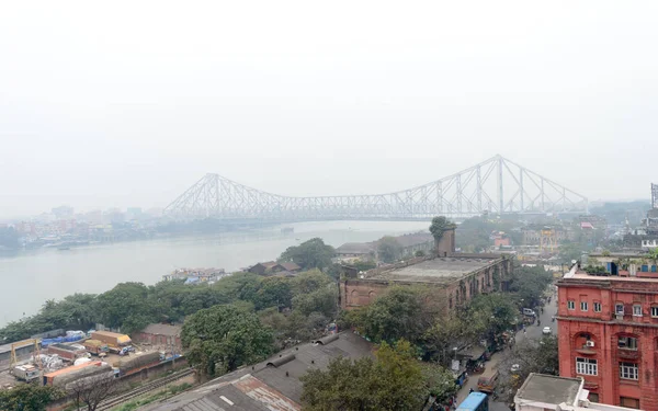 Vista aerea Cityscape Howrah Bridge (Rabindra Setu) della vita cittadina di Calcutta sulla riva del fiume Hooghly vicino alla zona di Burrabazar in una nebbiosa giornata serale invernale. Kolkata West Bengal India Asia Meridionale Pac gennaio 2020 — Foto Stock