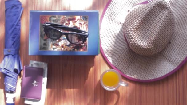 夏の女性旅行アクセサリーのトップビューのビーチの背景 サングラス お金の財布 麦藁帽子とジュースのガラス テキストのためのコピースペースと夏休みの休暇のコンセプト — ストック動画