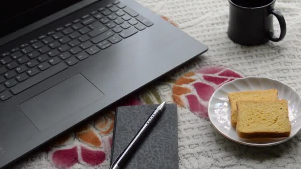 早餐咖啡在早晨的阳光下 笔记本电脑黑色钢笔和个人记事本 陶瓷杯茶托和饼干在办公室顶部的工作台背景 生活方式形象 — 图库视频影像