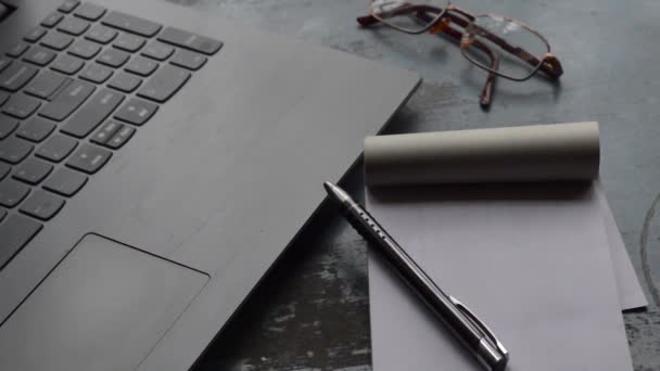 ノートパソコンの黒い色のペンと白の支配紙のノートブックと朝の日差しの中で朝食コーヒー 錆の色の表面の背景にオフィスの作業机の上のセラミックカップ ライフスタイルイメージ — ストック動画
