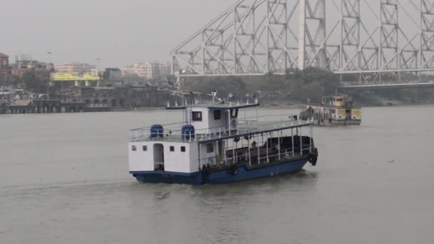 コルカタとハウラー市を結ぶガンジス川の西ベンガル海運表面輸送公社 Wbstc による旅客フェリーサービスステーションを運ぶ船 遠くにあるハワラ橋 インド 南アジア太平洋 — ストック動画