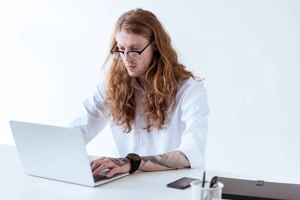 şık dövmeli işadamı kıvırcık saçlı ofiste dizüstü bilgisayar ile çalışma