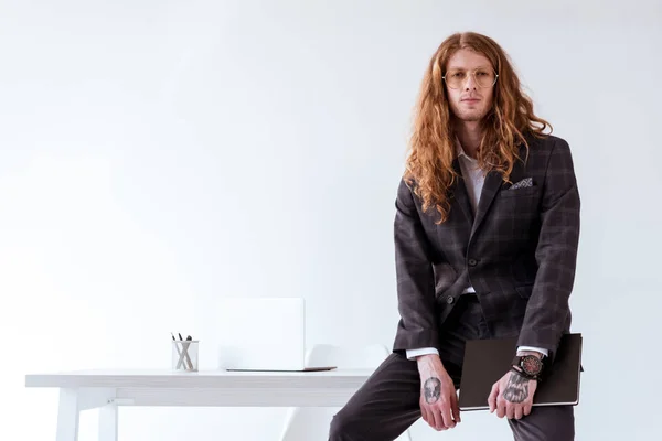 kıvırcık saçlı tablo ve holding klasör üzerinde oturan işadamı şık dövme