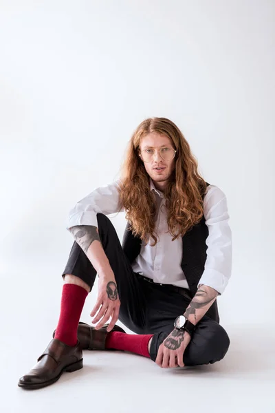 katta oturan ve kameraya beyaz görünümlü kıvırcık saçlı şık dövmeli işadamı