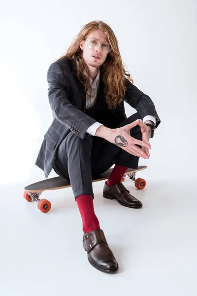 kıvırcık saçlı kaykay üzerinde oturan şık iş adamı