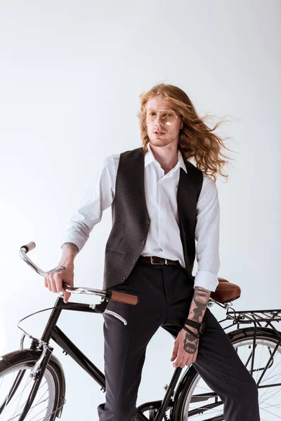 Elegante uomo d'affari tatuato con i capelli ricci seduto sulla bicicletta isolato su bianco — Foto stock