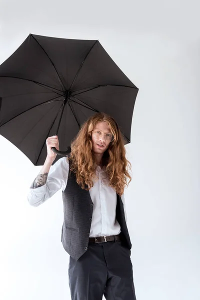 Schöner Geschäftsmann mit lockigem Haar steht unter schwarzem Regenschirm isoliert auf weißem Grund — Stockfoto