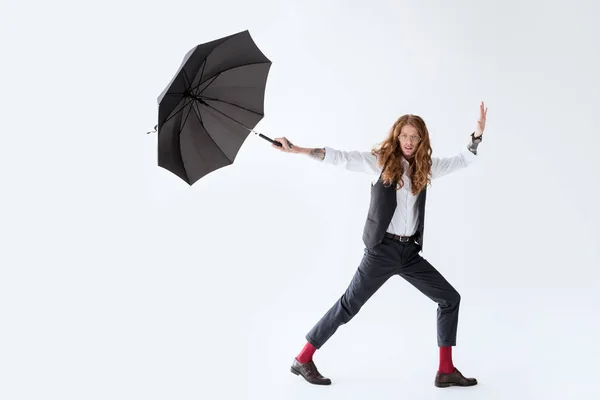 Schöner Geschäftsmann mit lockigem Haar hat Spaß mit schwarzem Regenschirm auf weißem Hintergrund — Stockfoto