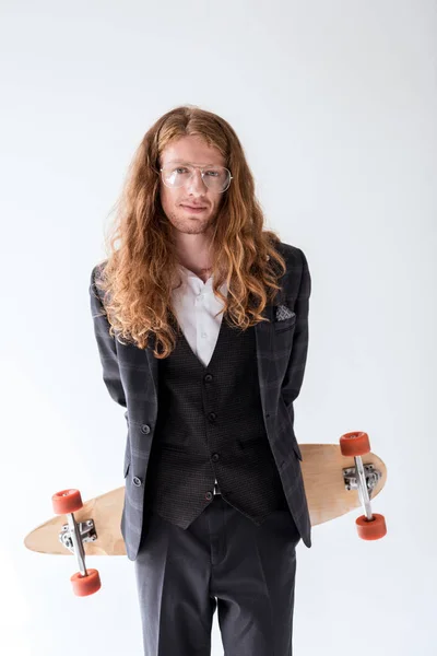 Stylischer Geschäftsmann mit lockigem Haar hält Longboard über Rücken isoliert auf weiß — Stockfoto