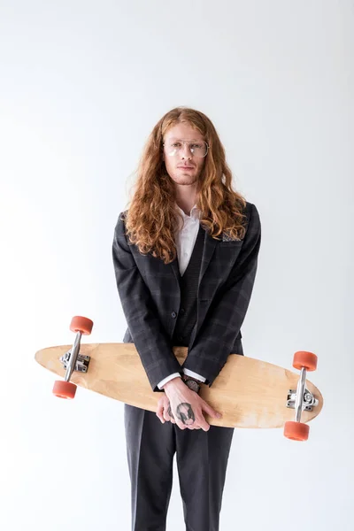Stylischer Geschäftsmann mit lockigem Haar hält Longboard isoliert auf weiß — Stockfoto