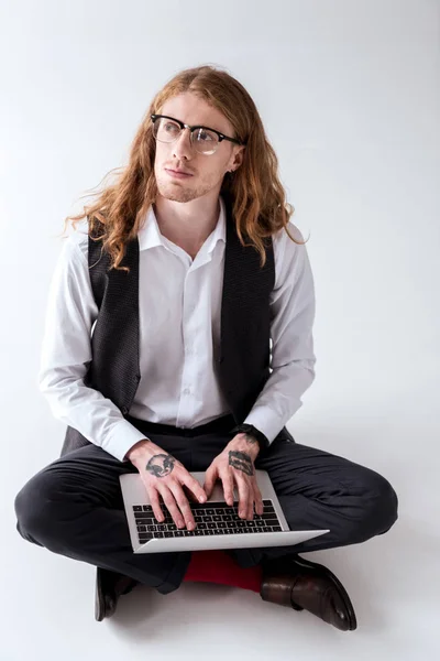 Homem de negócios tatuado elegante com cabelo encaracolado sentado no chão com laptop — Fotografia de Stock