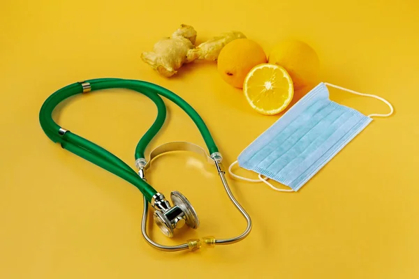 Concept healthcare. Stethoscope, medical mask and natural vitamins, lemon with ginger on a yellow background. Prevention and diagnosis of coronavirus in patients.