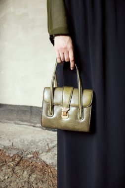 Yeşil gömlek ve siyah elbise, gri beton zemin üzerine yeşil deri el çantası ile. Moda ve şık konsept.