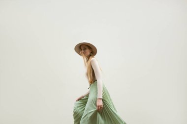 Şapkalı, Kızıl saçlı genç kız kılığında bej bluz ve gezinti pileler etek, ışık sokak backgraund üzerinde. Moda ve şık konsept.