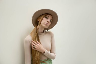 Şapkalı, Kızıl saçlı genç kız kılığında bej bluz ve gezinti pileler etek, ışık sokak backgraund üzerinde. Moda ve şık konsept.